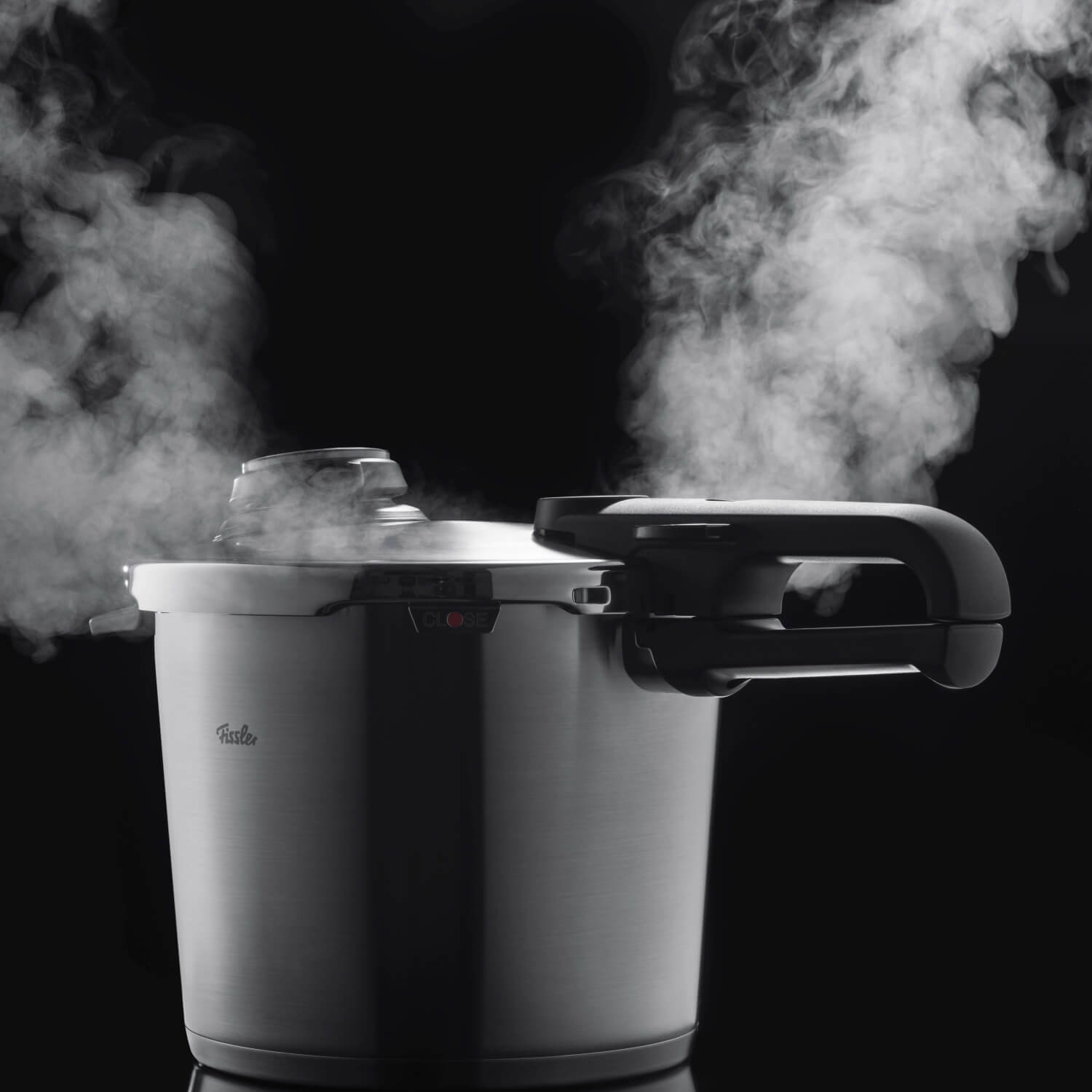 Ein dampfender Schnellkochtopf von Fissler mit modernem Design – stilvoll inszeniert vor schwarzem Hintergrund