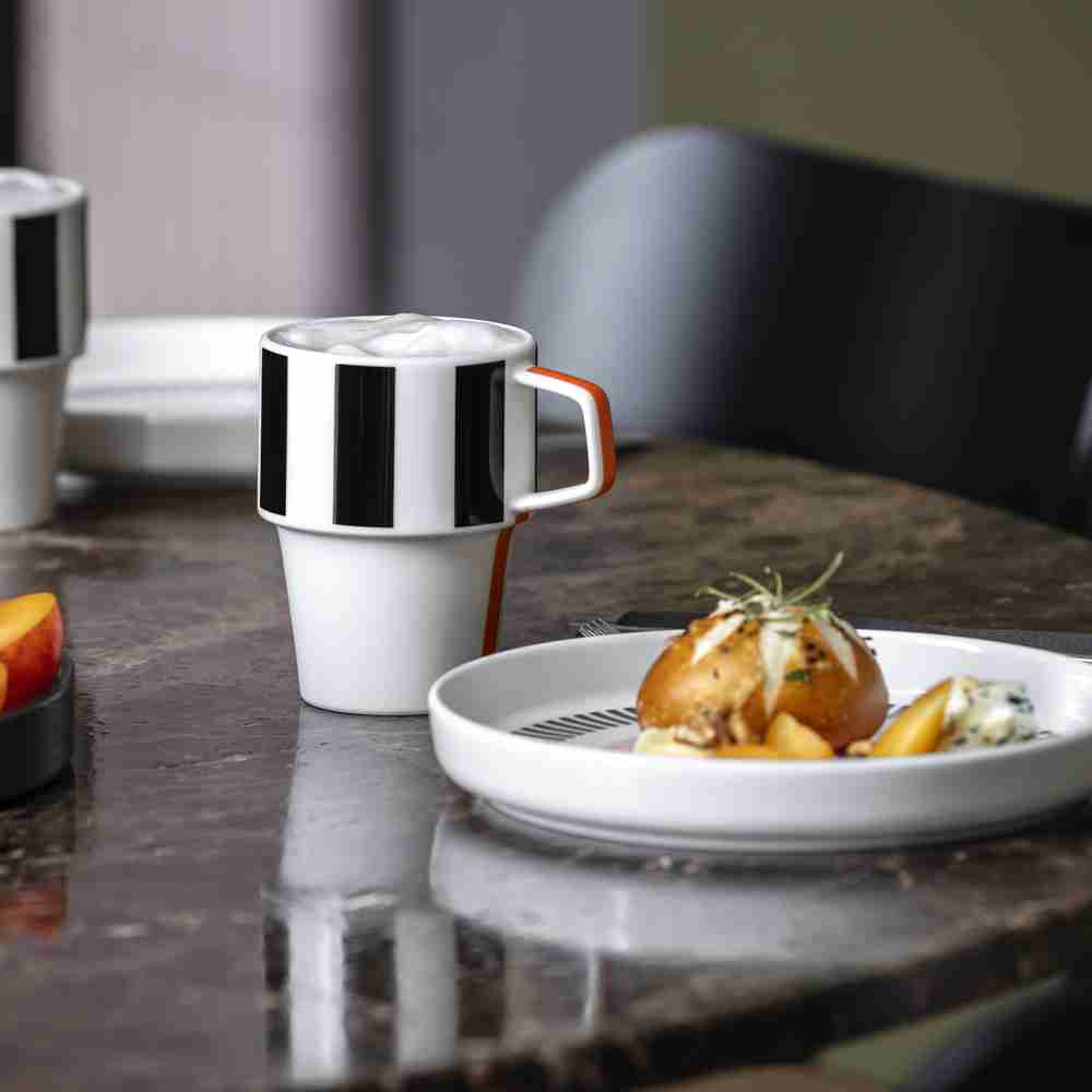 Villeroy und Boch Signature Henkelbecher Memphis als Teil eines Gedecks Der Villeroy & Boch Signature Henkelbecher Memphis, gefüllt mit Kaffee, als Teil eines stilvollen Gedecks mit Speisen auf einem Tisch.