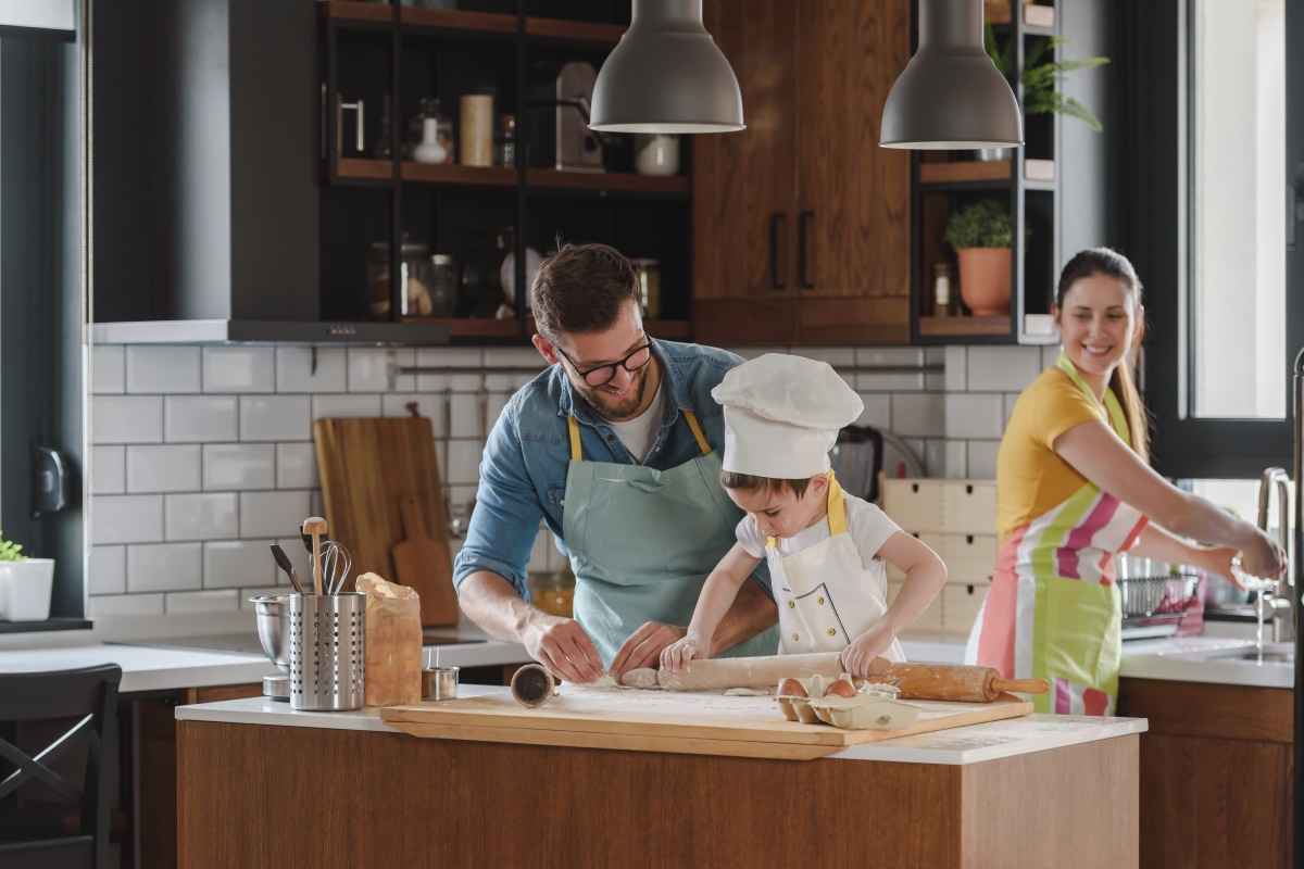 Eine Familie in einer schönen Küche, Kind und Vater backen, die Mutter kocht