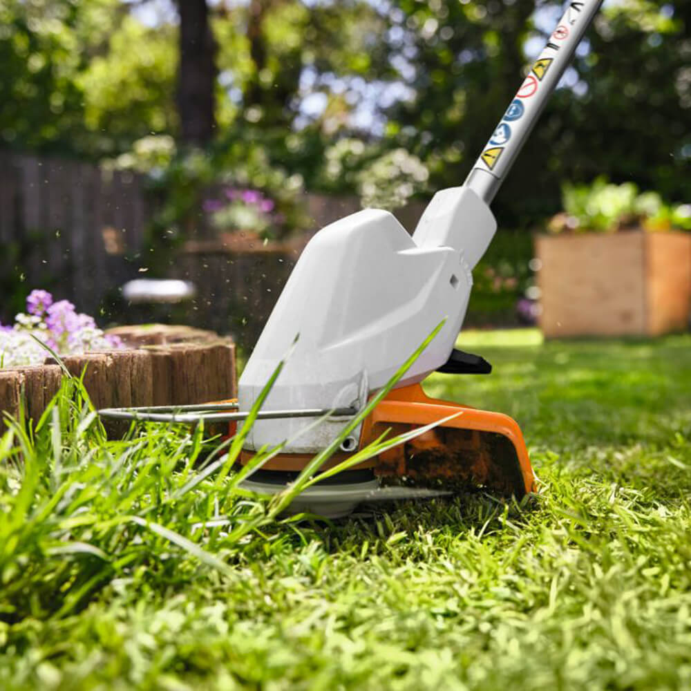 Eine Nahaufnahme zeigt den Mähkopf der akkubetriebenen Stihl Motorsense FSA 30 (AS-System, Solo) im Einsatz beim Trimmen von Gras.